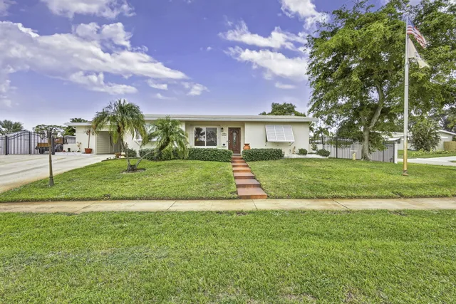 a view of a house with a big yard and palm trees
