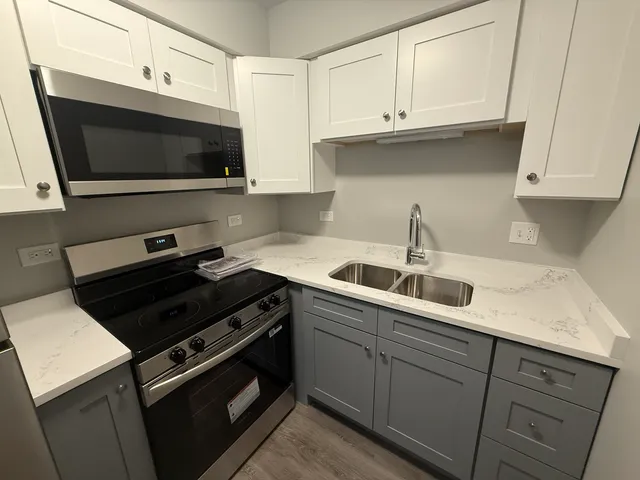 a kitchen with granite countertop white cabinets and black appliances