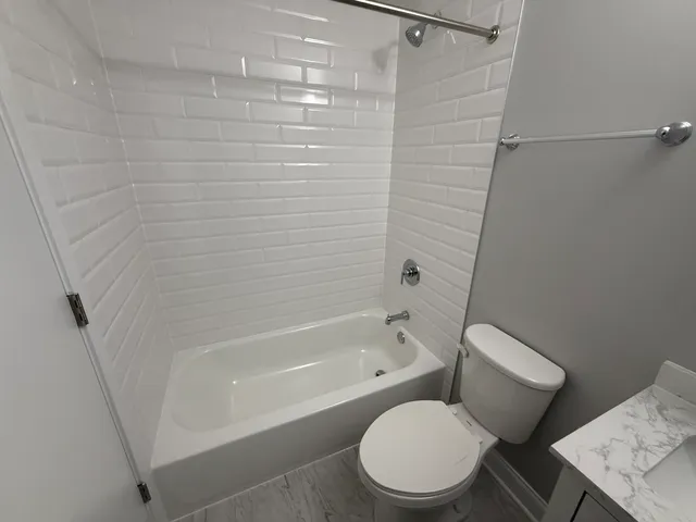 a white toilet and tub sitting next to a bathroom sink