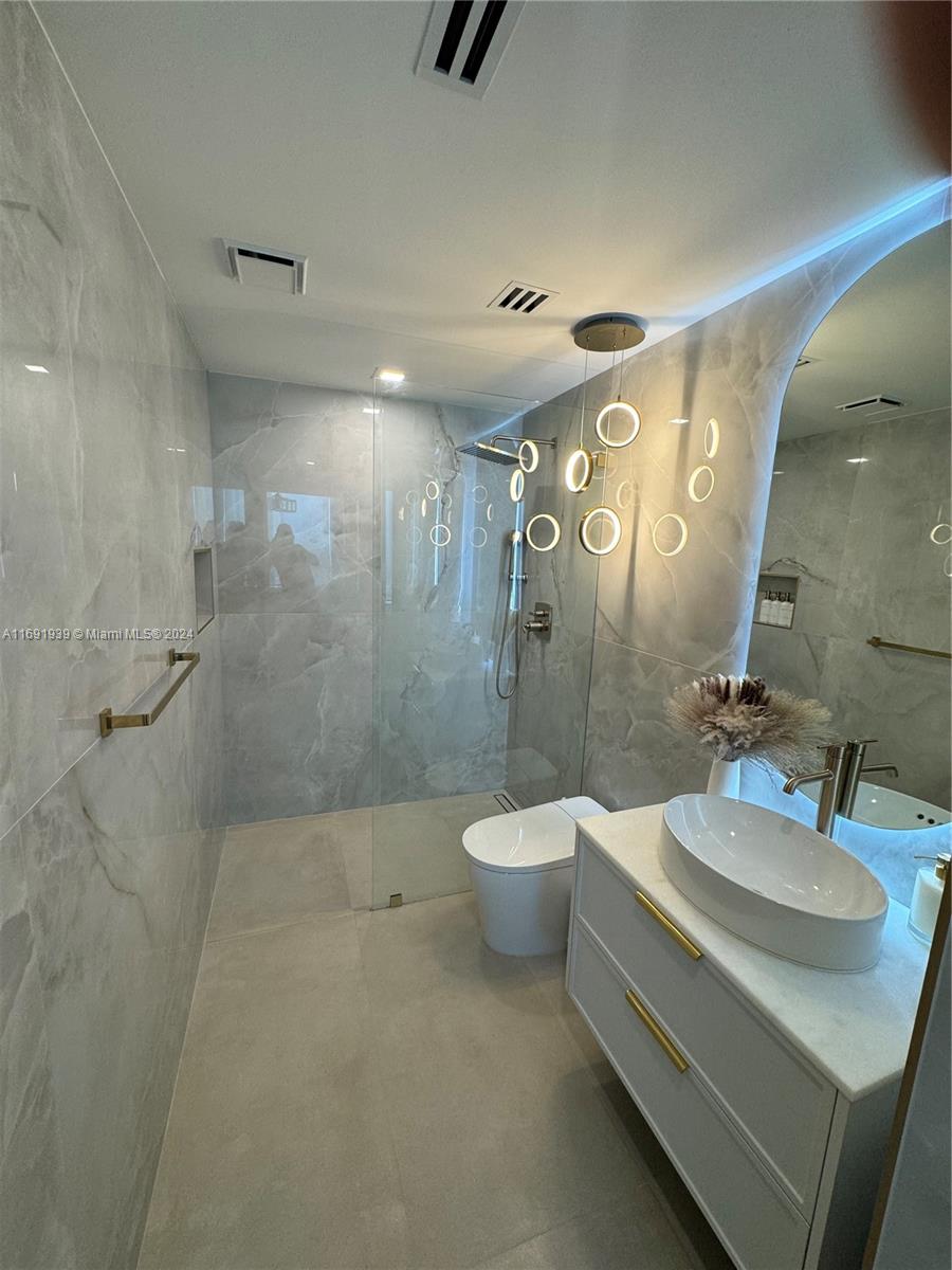 90 Southwest 3rd Street, Unit PH15 Miami, FL 33130 - Photo 11 of 18 a bathroom with a double vanity sink toilet and shower