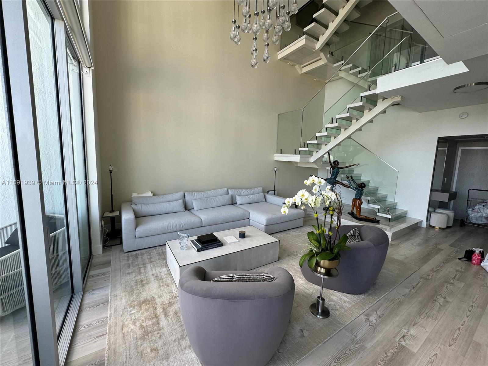 90 Southwest 3rd Street, Unit PH15 Miami, FL 33130 - Photo 13 of 18 a living room with furniture and a chandelier