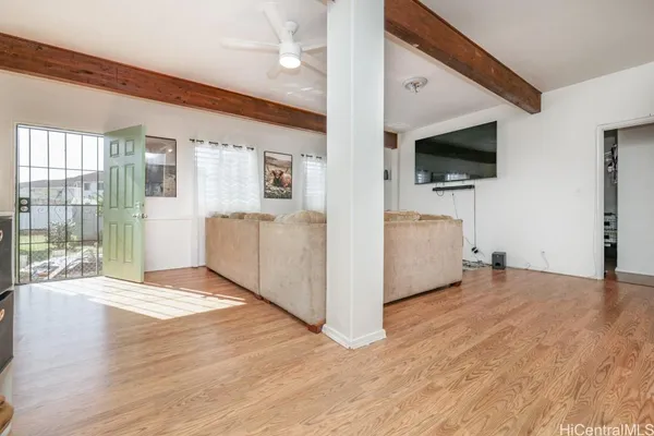 a view of a livingroom with an empty room and a kitchen space with wooden floor