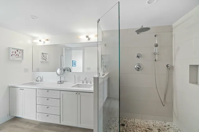 a bathroom with a double vanity sink mirror and shower