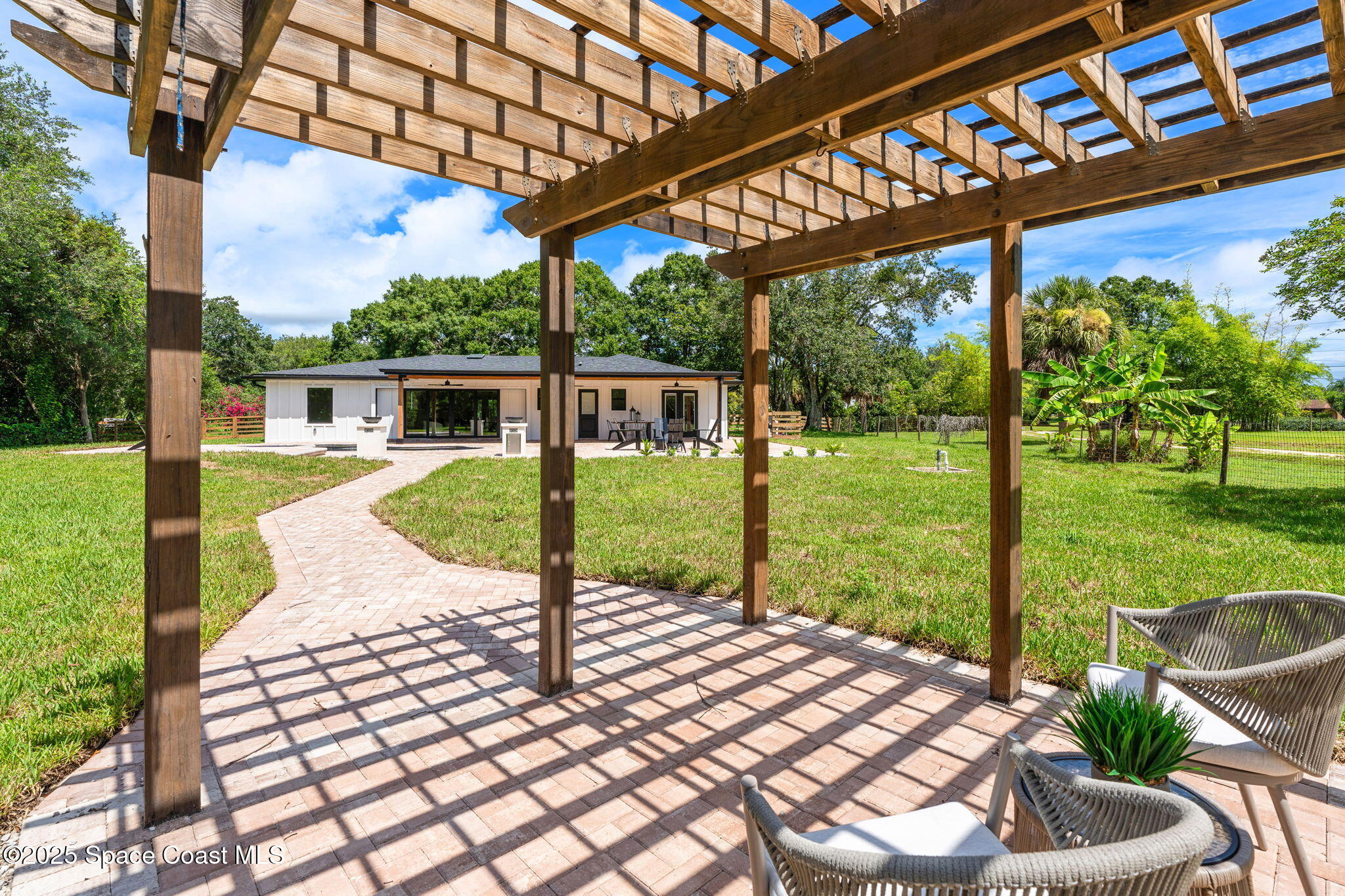 4313 Country Road Melbourne, FL 32934 - Photo 40 of 58 a view of a patio with a table chairs potted plants and palm trees