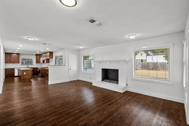 an empty room with wooden floor and a kitchen