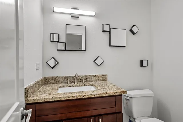 a bathroom with a granite countertop sink a toilet and mirror