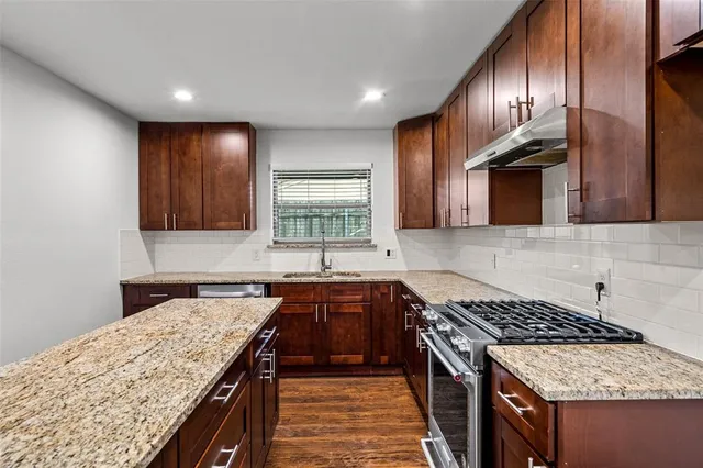 a kitchen with granite countertop stainless steel appliances a sink stove and cabinets