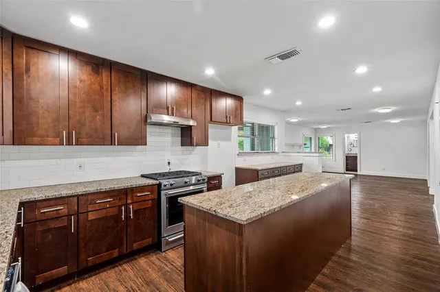 a large kitchen with stainless steel appliances granite countertop wooden cabinets a oven and granite counter tops with a large window