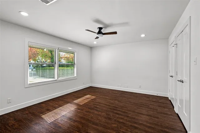 an empty room with wooden floor ceiling fan and windows