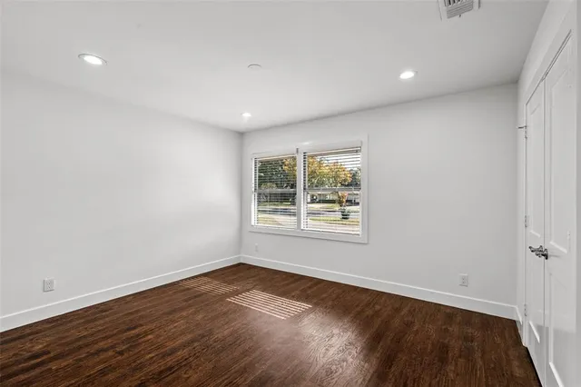 an empty room with wooden floor and window