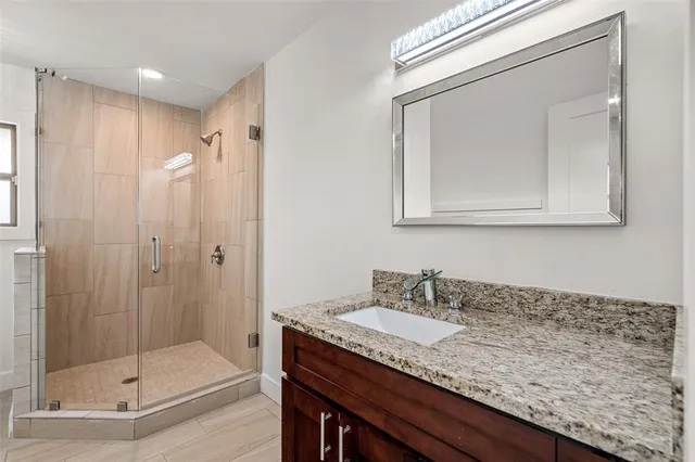 a bathroom with a granite countertop sink a mirror and shower