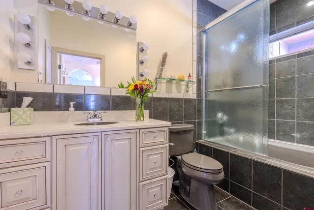 a bathroom with a granite countertop sink a toilet and shower