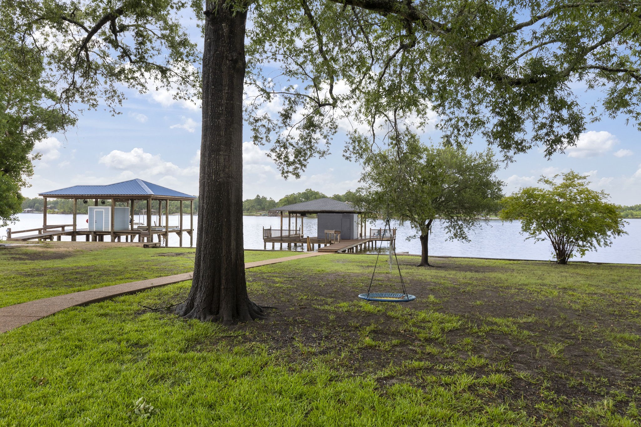 245 Lakeland Road Huntsville, TX 77320 - Photo 44 of 49 A backyard oasis with lakefront views, featuring mature trees and a charming swing for relaxation