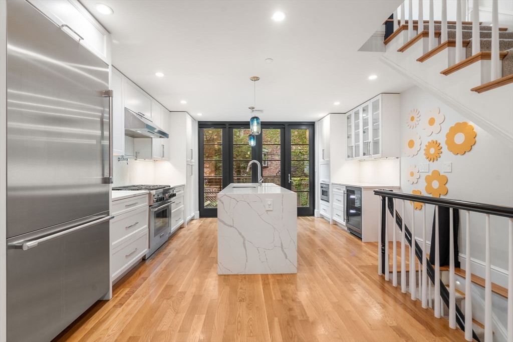 a kitchen with stainless steel appliances granite countertop a refrigerator a stove and a wooden floors