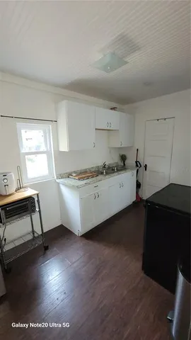 a room with kitchen island a sink wooden floor and black appliances