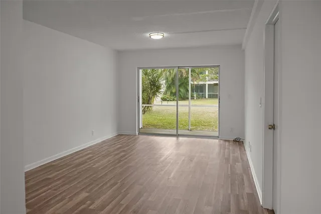 a view of an empty room with wooden floor and a window