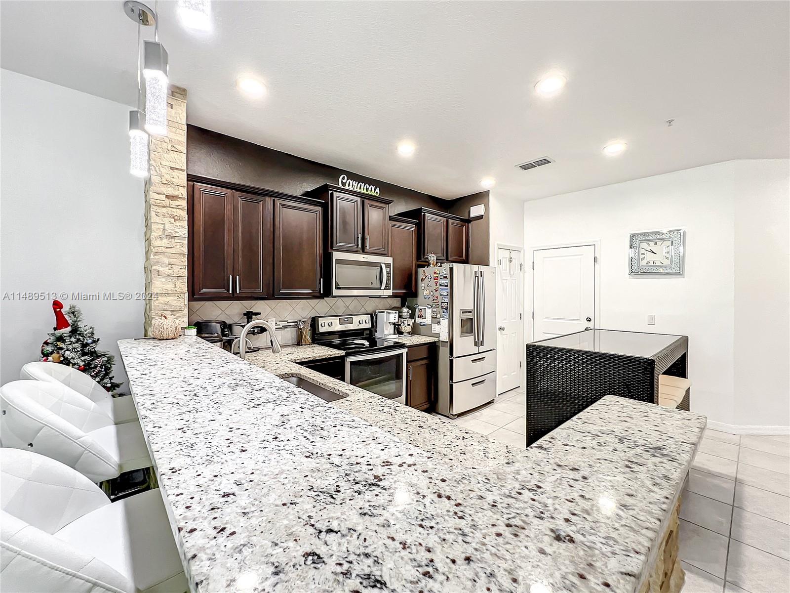 a kitchen with stainless steel appliances kitchen island granite countertop a refrigerator sink and wooden cabinets