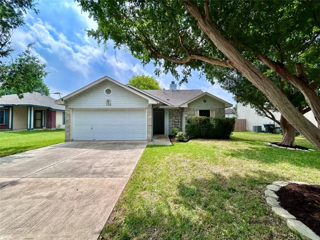 a front view of a house with a garden and trees
