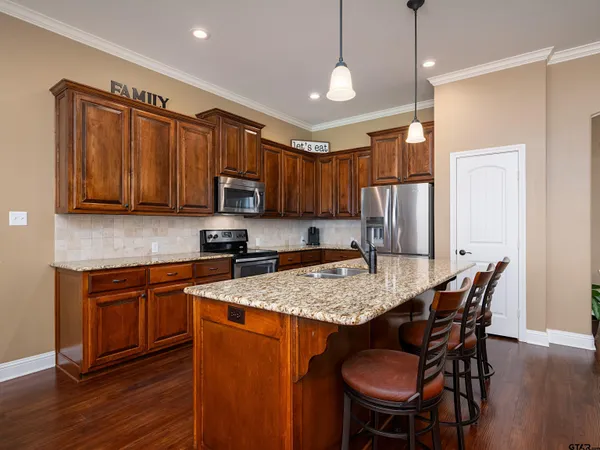 a kitchen with stainless steel appliances granite countertop wooden cabinets a stove a sink and a refrigerator