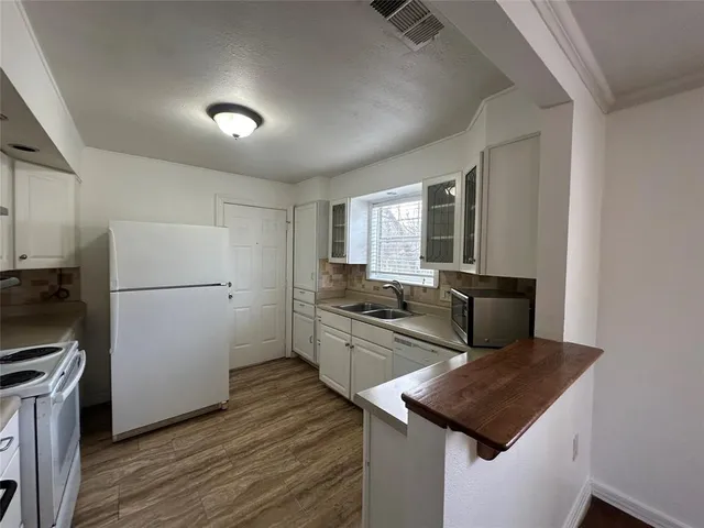 a kitchen that has a microwave a stove and wooden floor