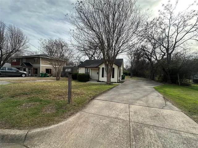 a view of a yard in front of a brick house with a fountain
