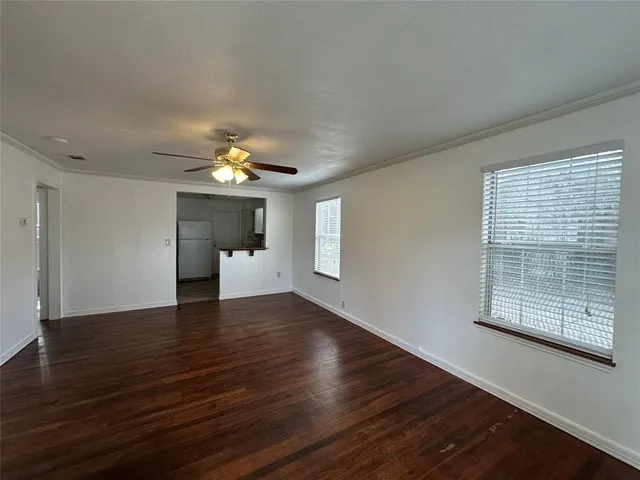an empty room with wooden floor chandelier and windows