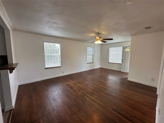 an empty room with wooden floor chandelier and windows