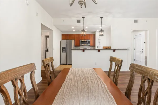 a kitchen with stainless steel appliances wooden floor dining table and chairs