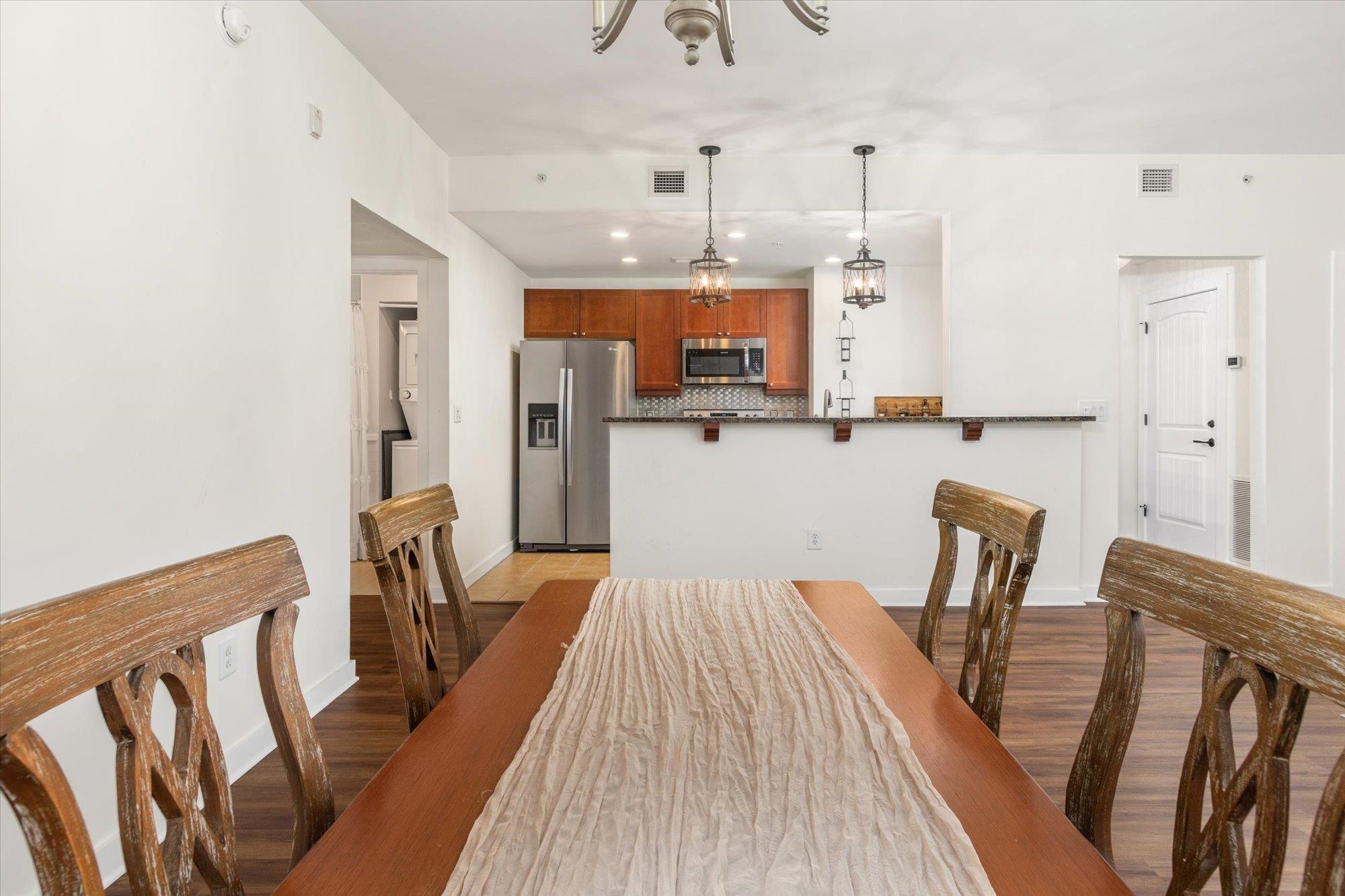 955 Registry Boulevard, Unit 105 St. Augustine, FL 32092 - Photo 16 of 30 a kitchen with stainless steel appliances wooden floor dining table and chairs