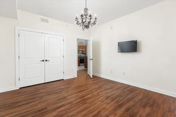 an empty room with wooden floor and chandelier