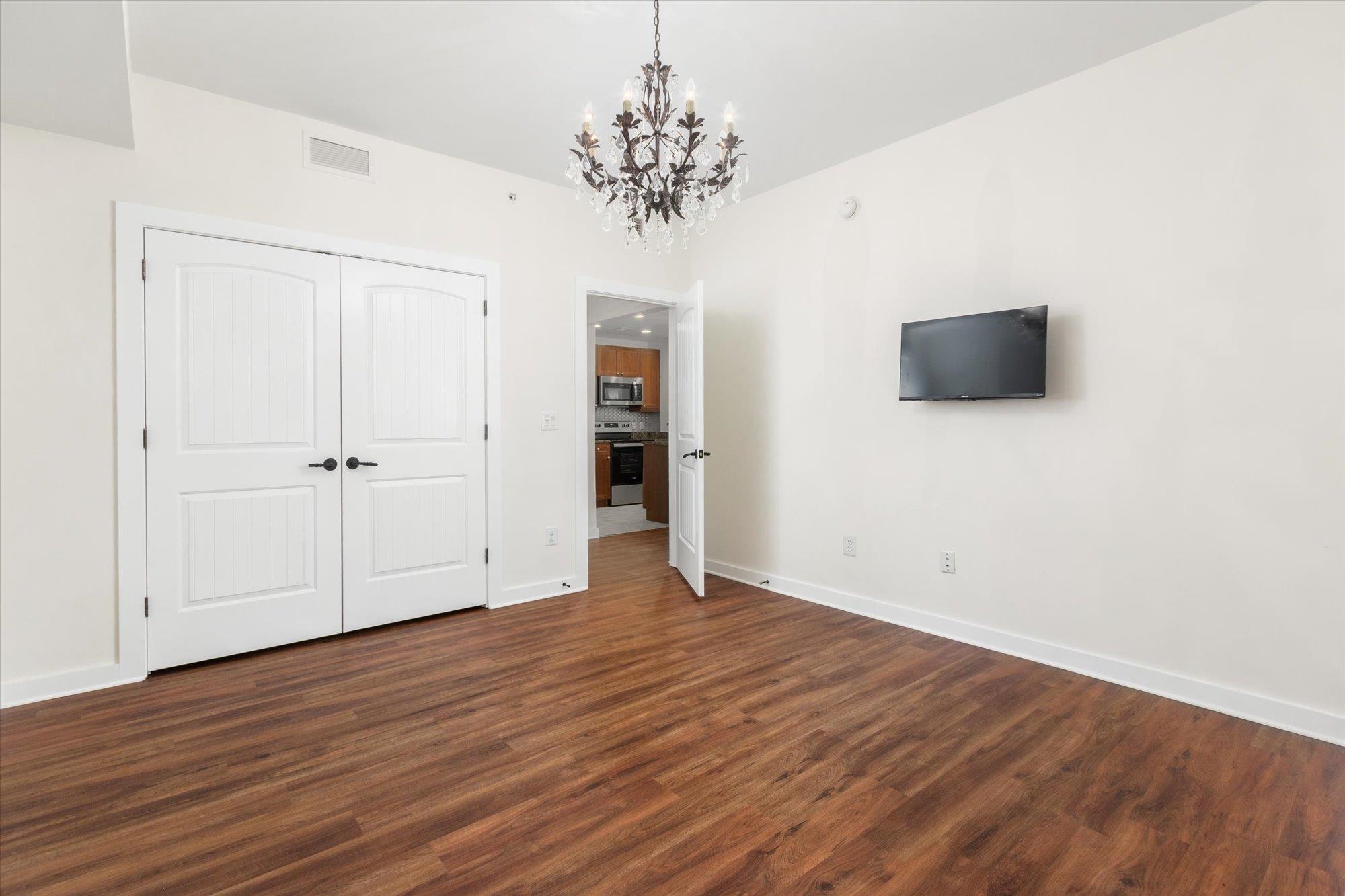 955 Registry Boulevard, Unit 105 St. Augustine, FL 32092 - Photo 20 of 30 an empty room with wooden floor and chandelier