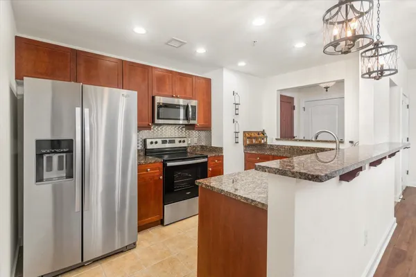 a kitchen with stainless steel appliances granite countertop a refrigerator a sink a stove a microwave and island