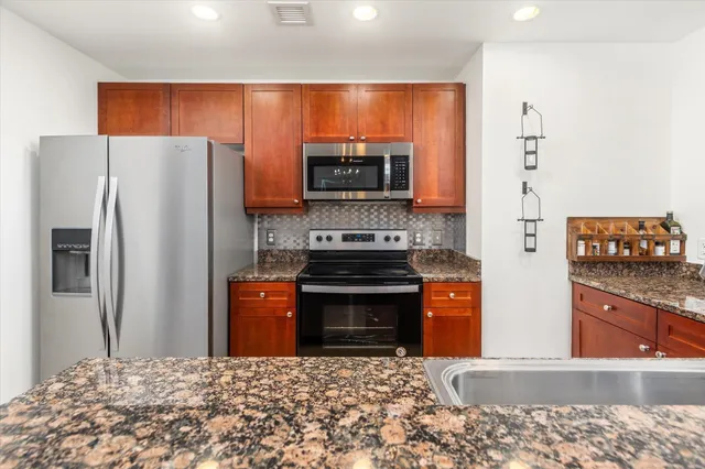 a kitchen with stainless steel appliances granite countertop a refrigerator stove and oven
