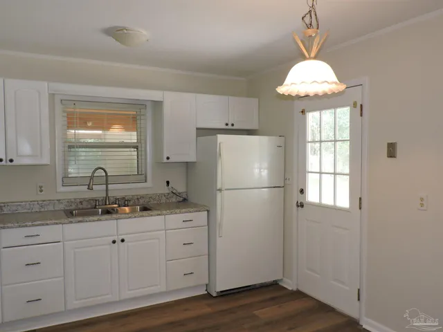 a kitchen with a refrigerator a sink dishwasher a stove and white cabinets with wooden floor