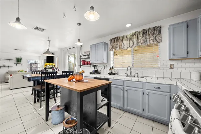 a kitchen with stainless steel appliances a table chairs sink and cabinets