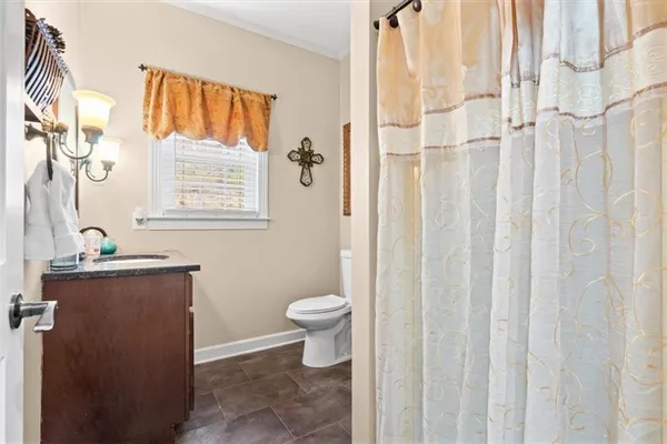 a bathroom with a granite countertop sink a toilet and a shower curtain