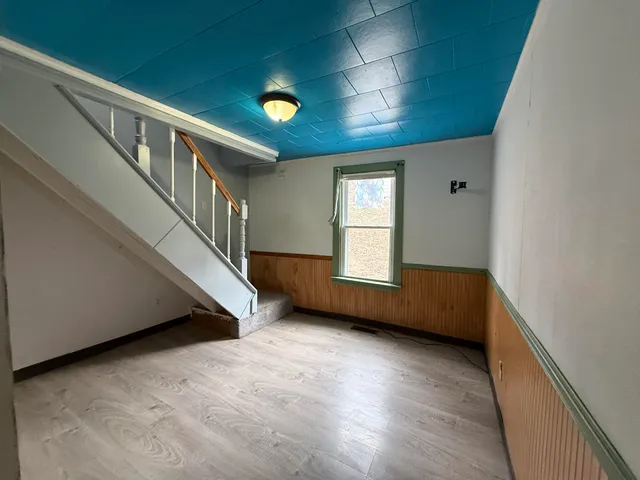 a view of an empty room with wooden floor and windows