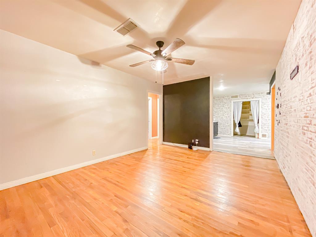 211 Paloma Street Winters, TX 79567 - Photo 2 of 19 a view of an empty room with chandelier fan and a hardwood floor