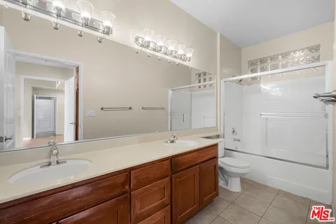 a spacious bathroom with a double vanity sink a toilet and a mirror