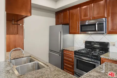 a kitchen with granite countertop a refrigerator stove and microwave
