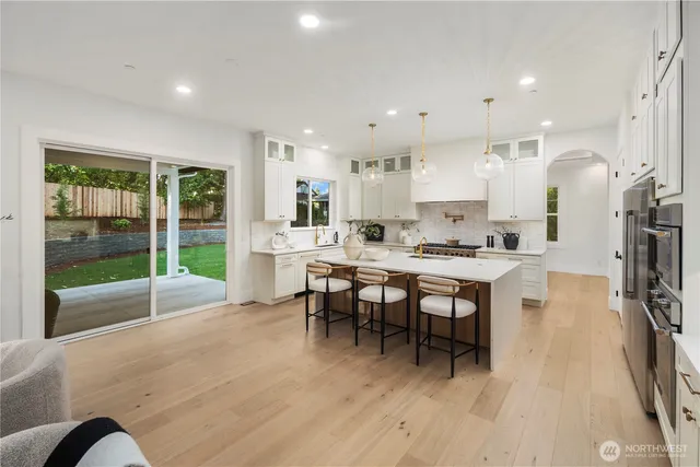 a open dining room with stainless steel appliances kitchen island granite countertop a table chairs and a view of living room