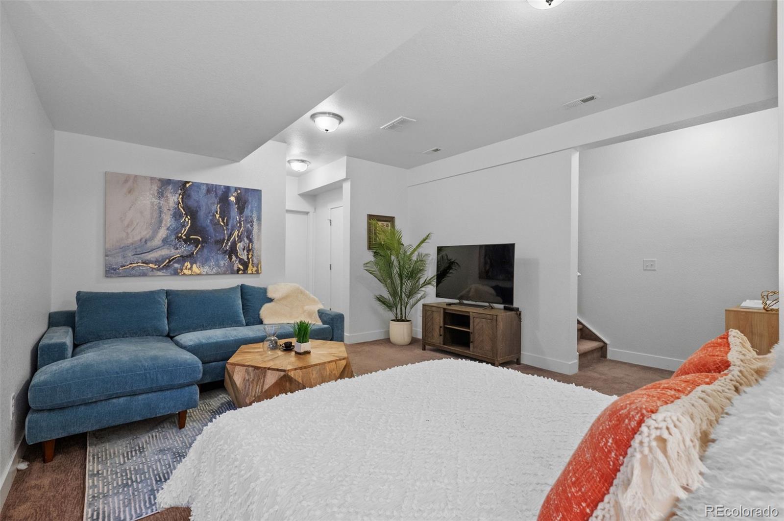 6817 Clay Street Denver, CO 80221 - Photo 23 of 41 a bedroom with a bed a couch and a flat screen tv