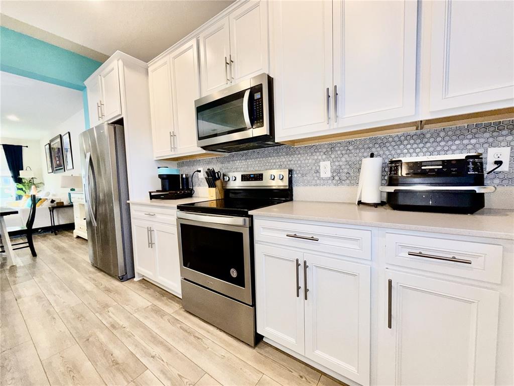 2208 Gopher Tortoise Terrace Oakland, FL 34787 - Photo 12 of 50 a kitchen with white cabinets and stainless steel appliances