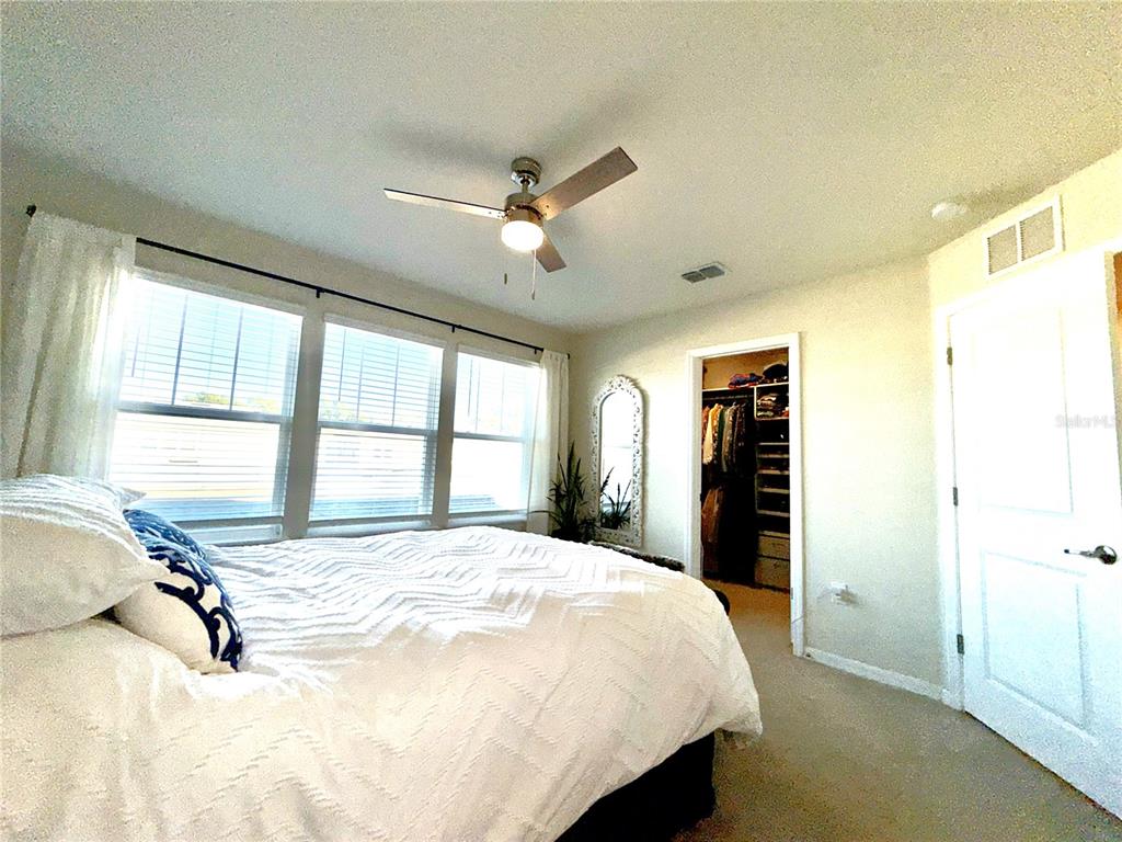 2208 Gopher Tortoise Terrace Oakland, FL 34787 - Photo 26 of 50 a bedroom with a bed and large windows