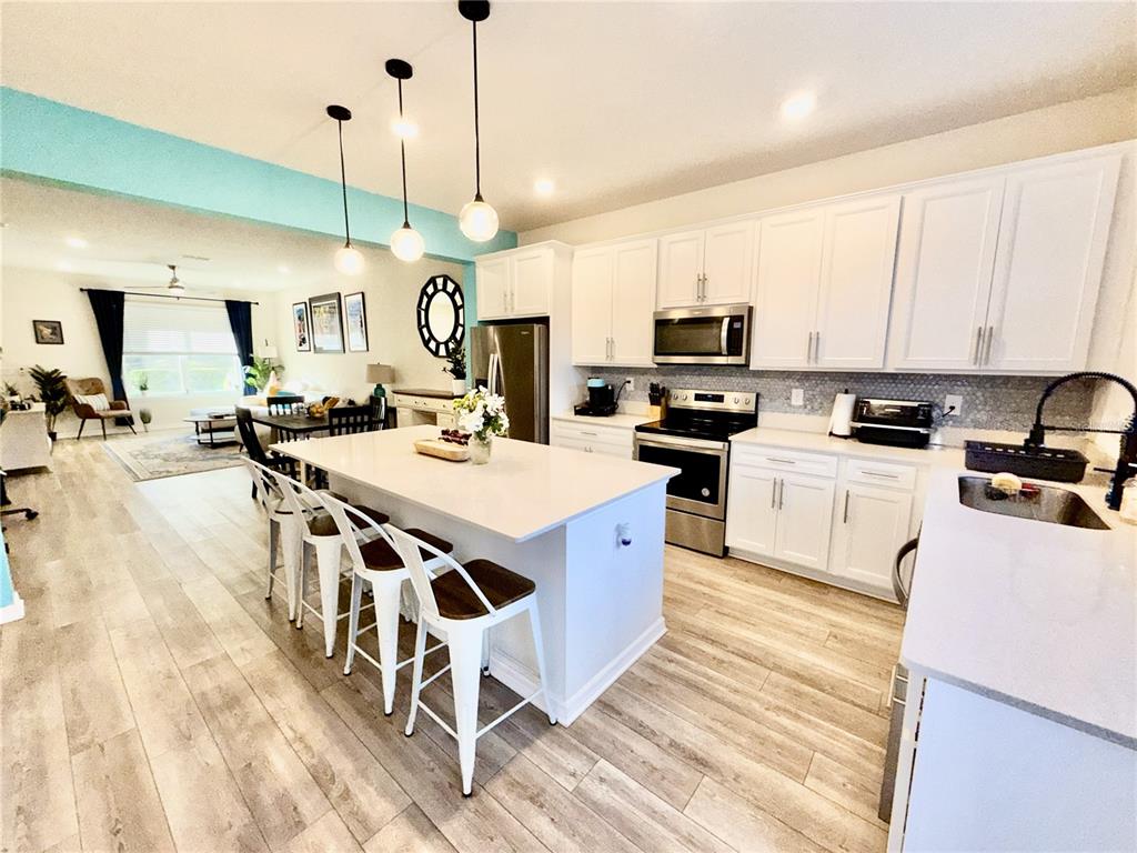 2208 Gopher Tortoise Terrace Oakland, FL 34787 - Photo 9 of 50 a kitchen with stainless steel appliances granite countertop a stove a sink dishwasher and a microwave with wooden floor