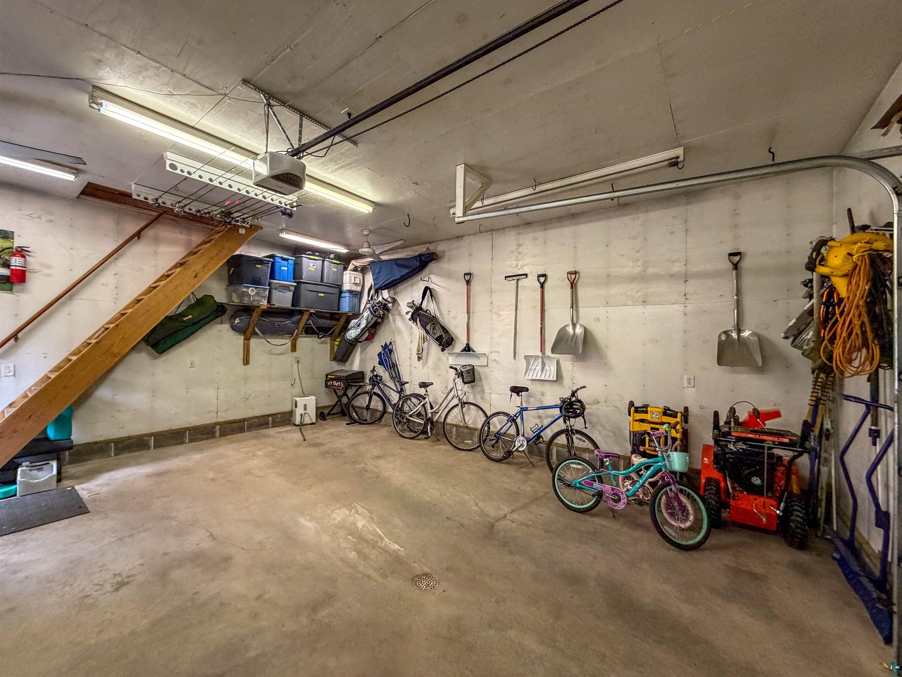 3704 Greysolon Road Duluth, MN 55804 - Photo 44 of 51 Concrete floor garage with exposed block walls, overhead fluorescent lighting, and a built-in wooden staircase