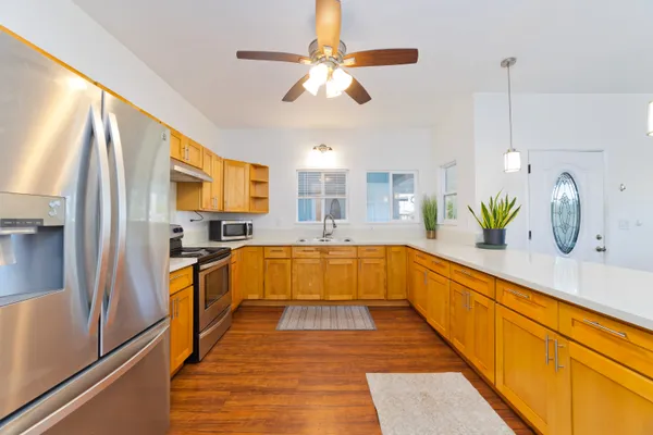 a large kitchen with stainless steel appliances a large counter top a stove a sink and a refrigerator