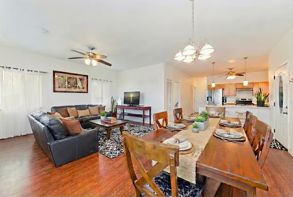 a living room with lots of furniture kitchen view and a chandelier