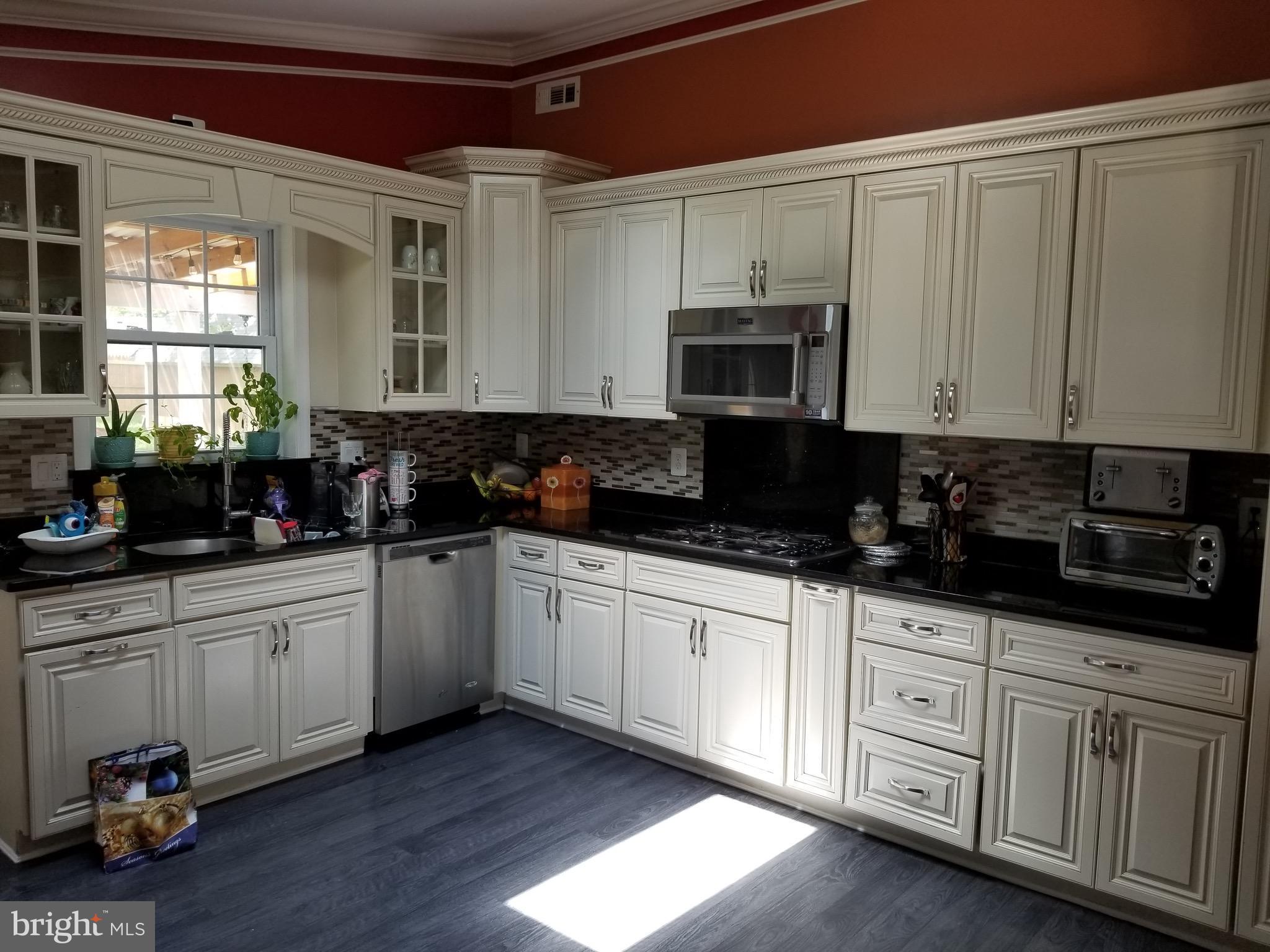 6218 Apache Street Springfield, VA 22150 - Photo 8 of 30 a kitchen with granite countertop white cabinets and black appliances