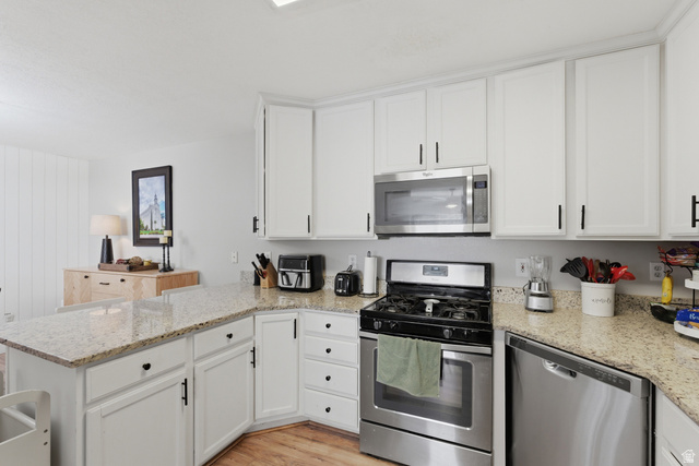 282 West 960 South, Unit C Provo, UT 84601 - Photo 9 of 33 Kitchen with stainless steel appliances, a peninsula, white cabinets, light wood-type flooring, and light stone countertops